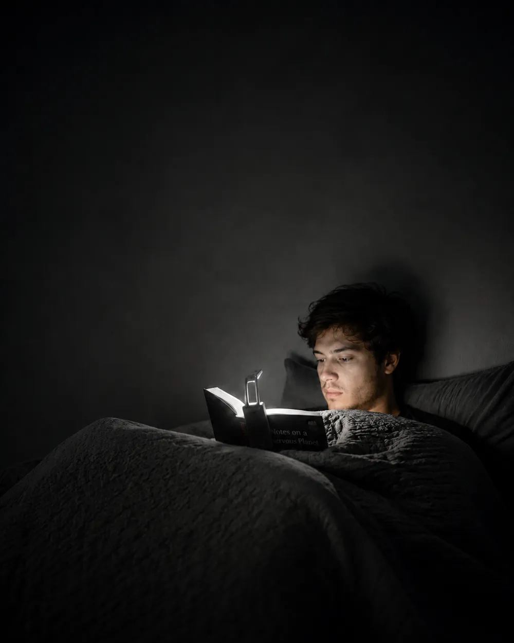 Persona leyendo en la cama con la luz VISIÓN